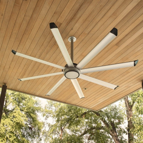 An image of a large, silver 8-blade fan attached to a wood ceiling. 